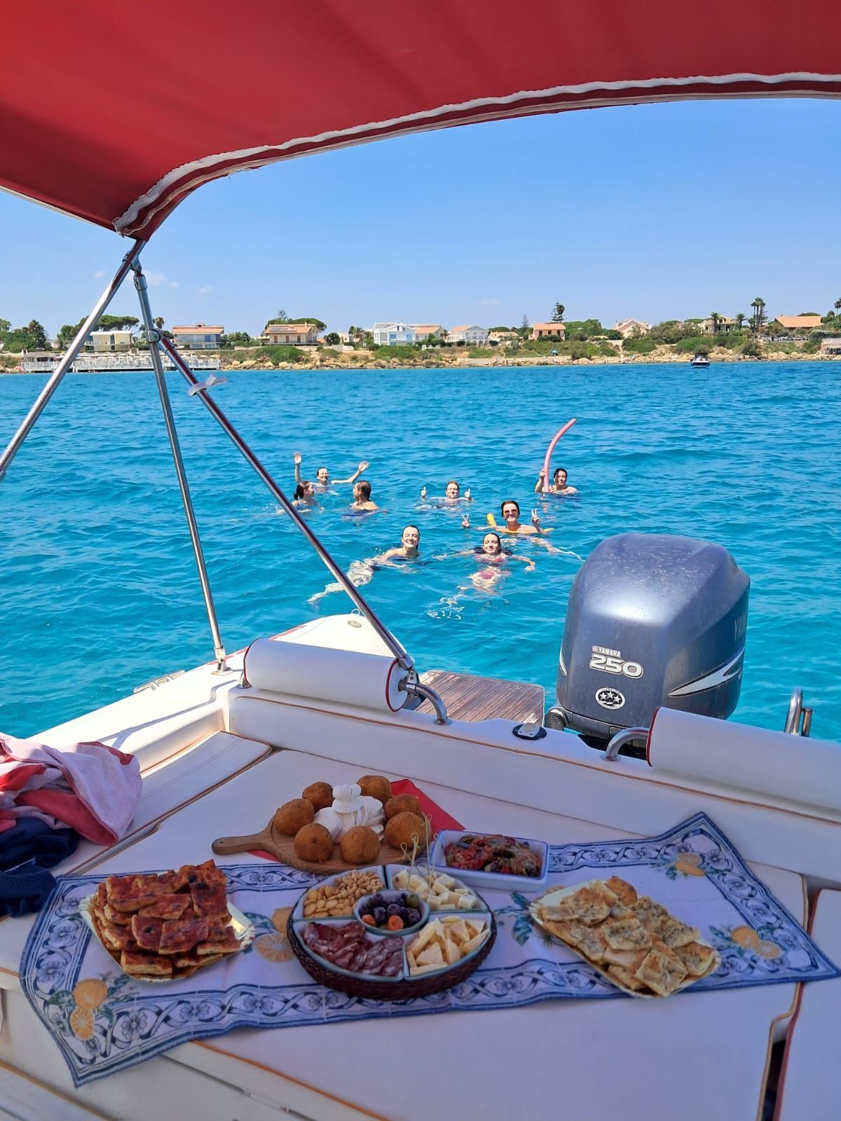 Aperitivo a bordo con ospiti che nuotano nel mare blu