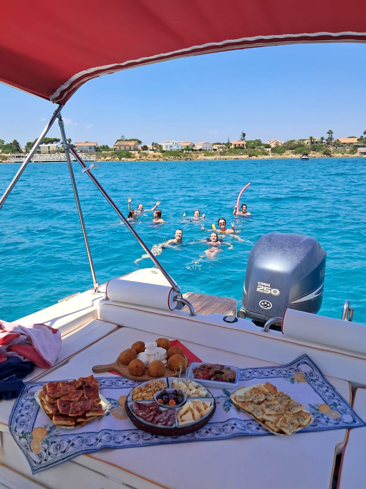 Aperitivo a bordo con ospiti che nuotano nel mare blu